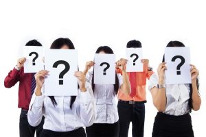 Colleagues holding question mark signs in front of their faces