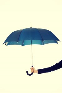Business woman's hand is holding blue umbrella.
