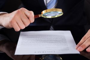 Businessman Examining Contract Paper With Magnifying Glass